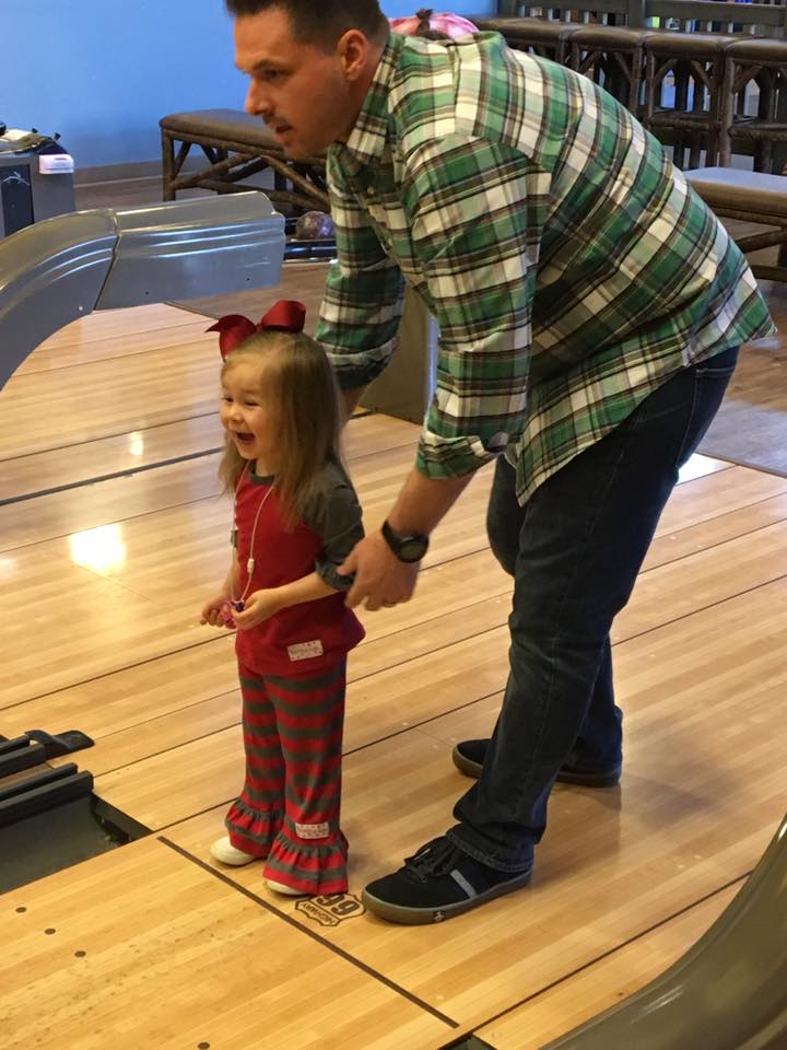 dad helping little girl bowl