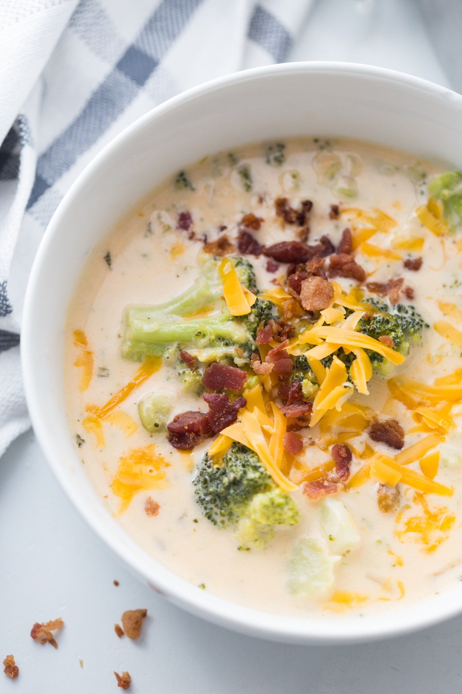 broccoli and cheese soup in a white bowl with toppings 