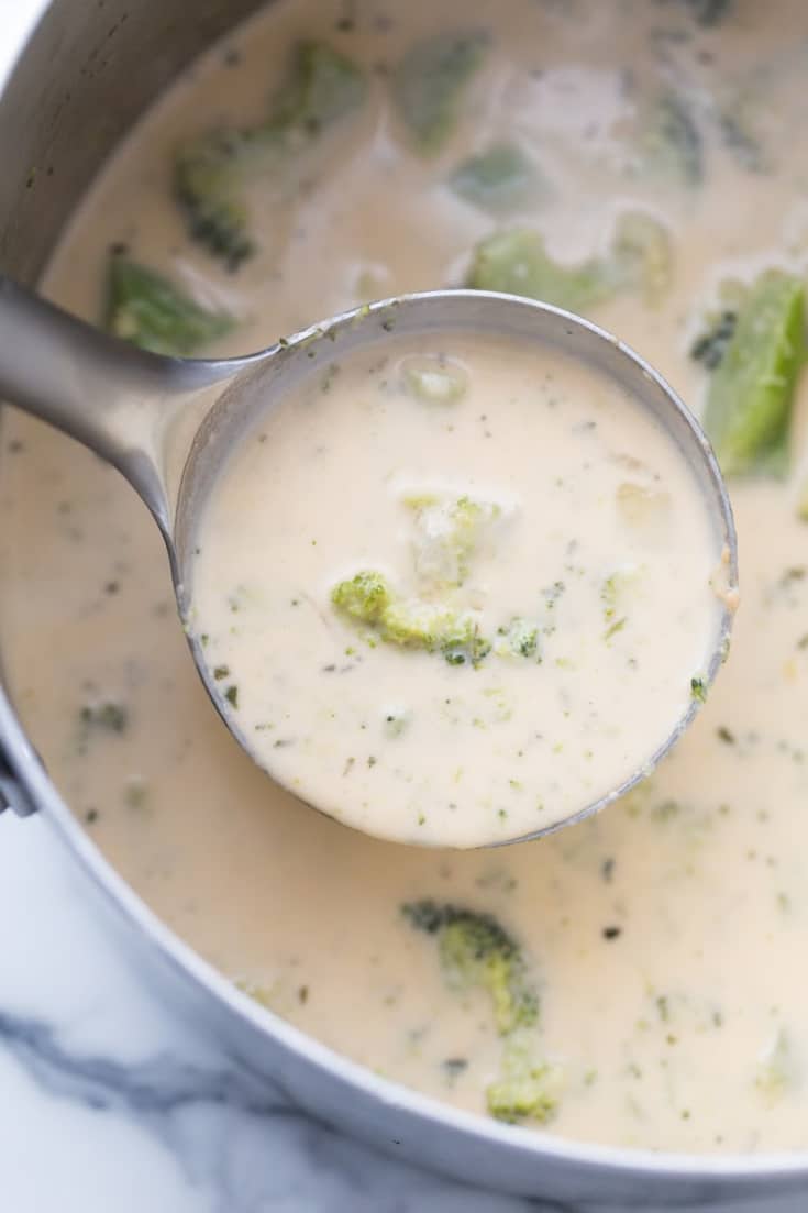 ladel of broccoli cheddar soup over saucepot