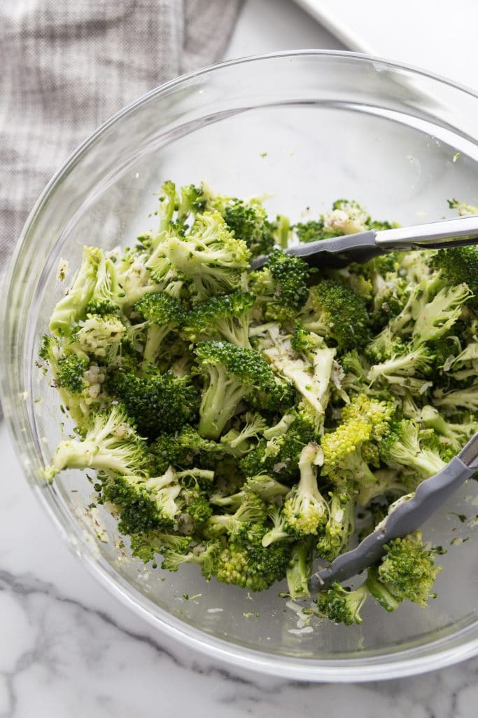 fresh broccoli in a bowl being tossed in oil and seasonings for oven baked pork chops recipe one pan meal