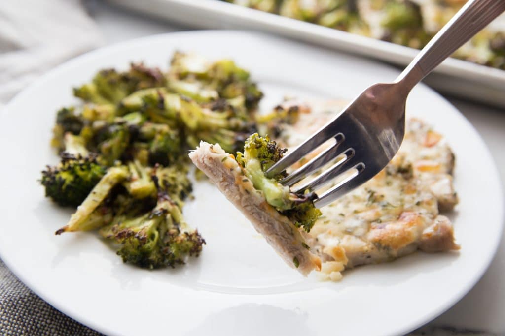 oven baked pork chops with broccoli plated with a bite on the fork