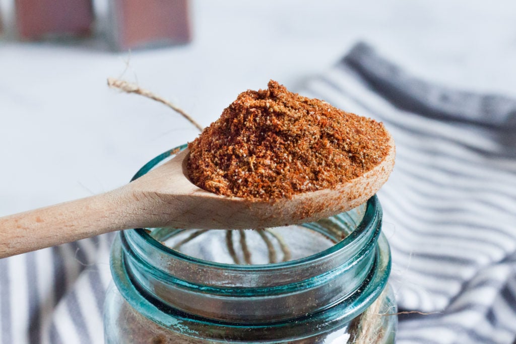 homemade low carb taco seasoning in a wooden spoon over a jar