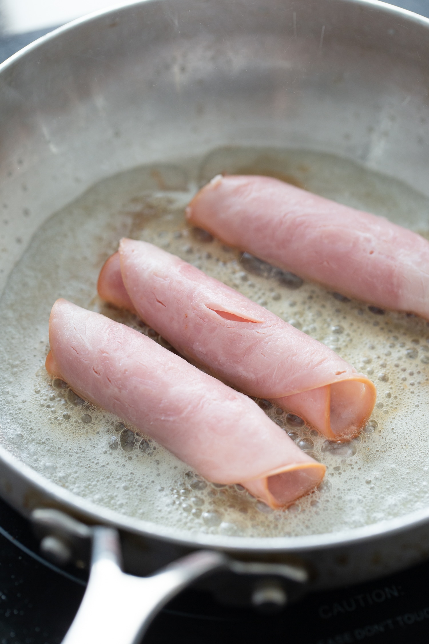 cheese wrapped in ham in a frying pan of butter for keto diet 