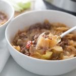 unstuffed cabbage soup in a white bowl with a bite on a spoon