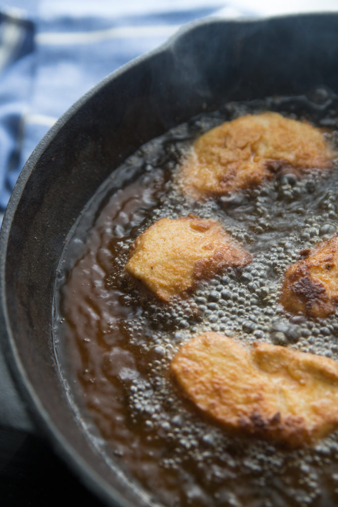 keto chicken nuggets deep frying in a cast iron skillet