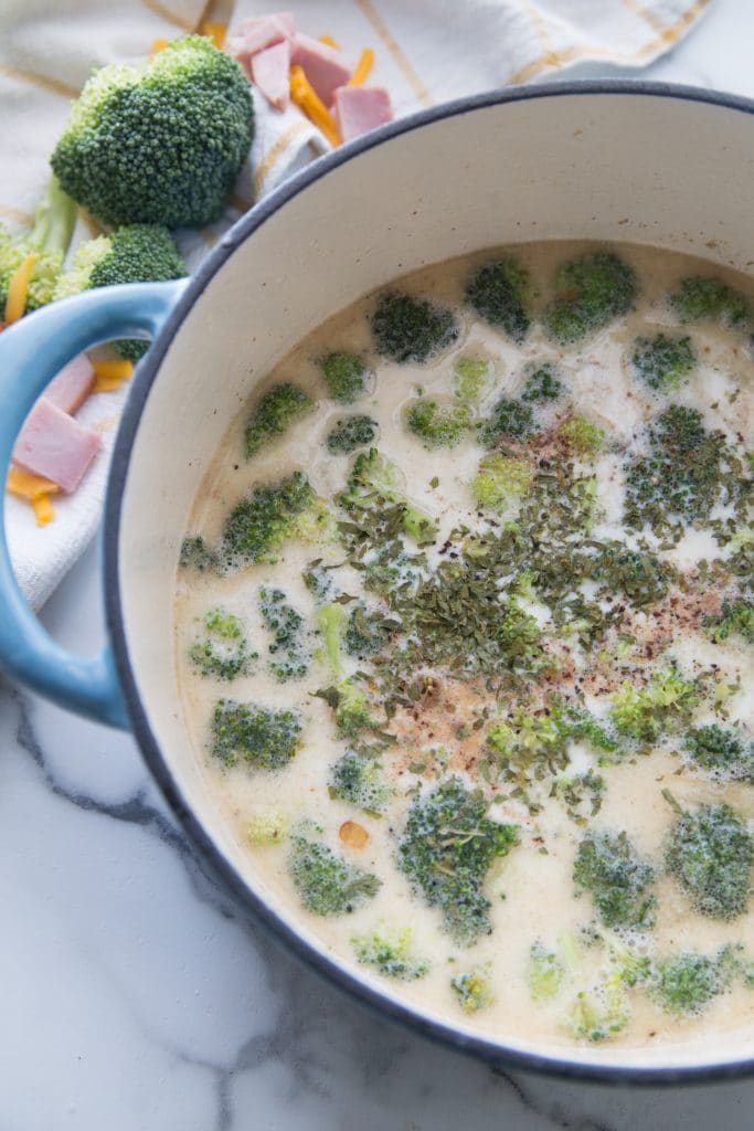 stock pot with broccoli, heavy whipping cream, cheese, and spices for keto ham soup