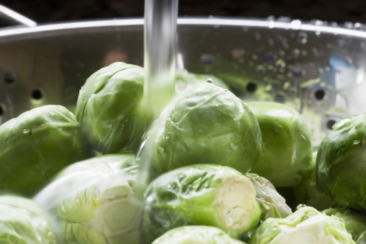 rinsing brussels sprouts in a colander for keto diet meal prep
