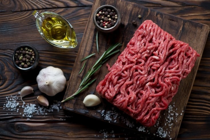 cutting board with raw ground beef on it along with spices for keto meal prep
