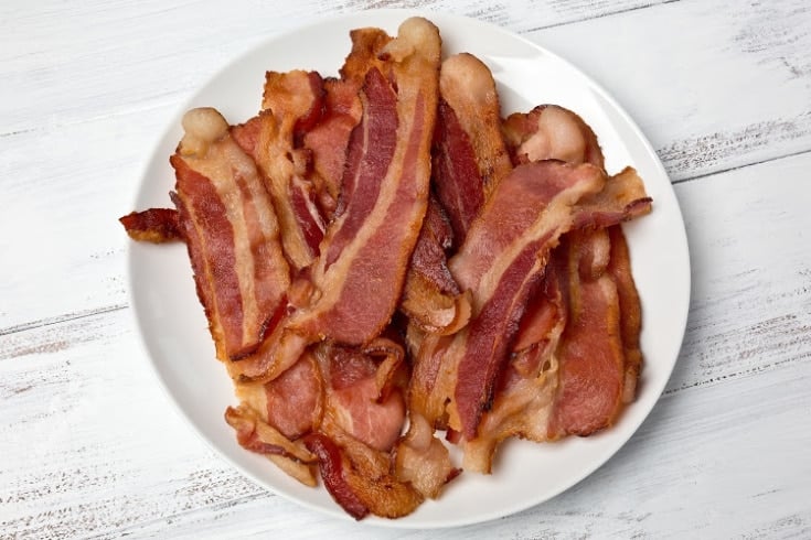 A small white plate of fried bacon strips for keto diet meal prep