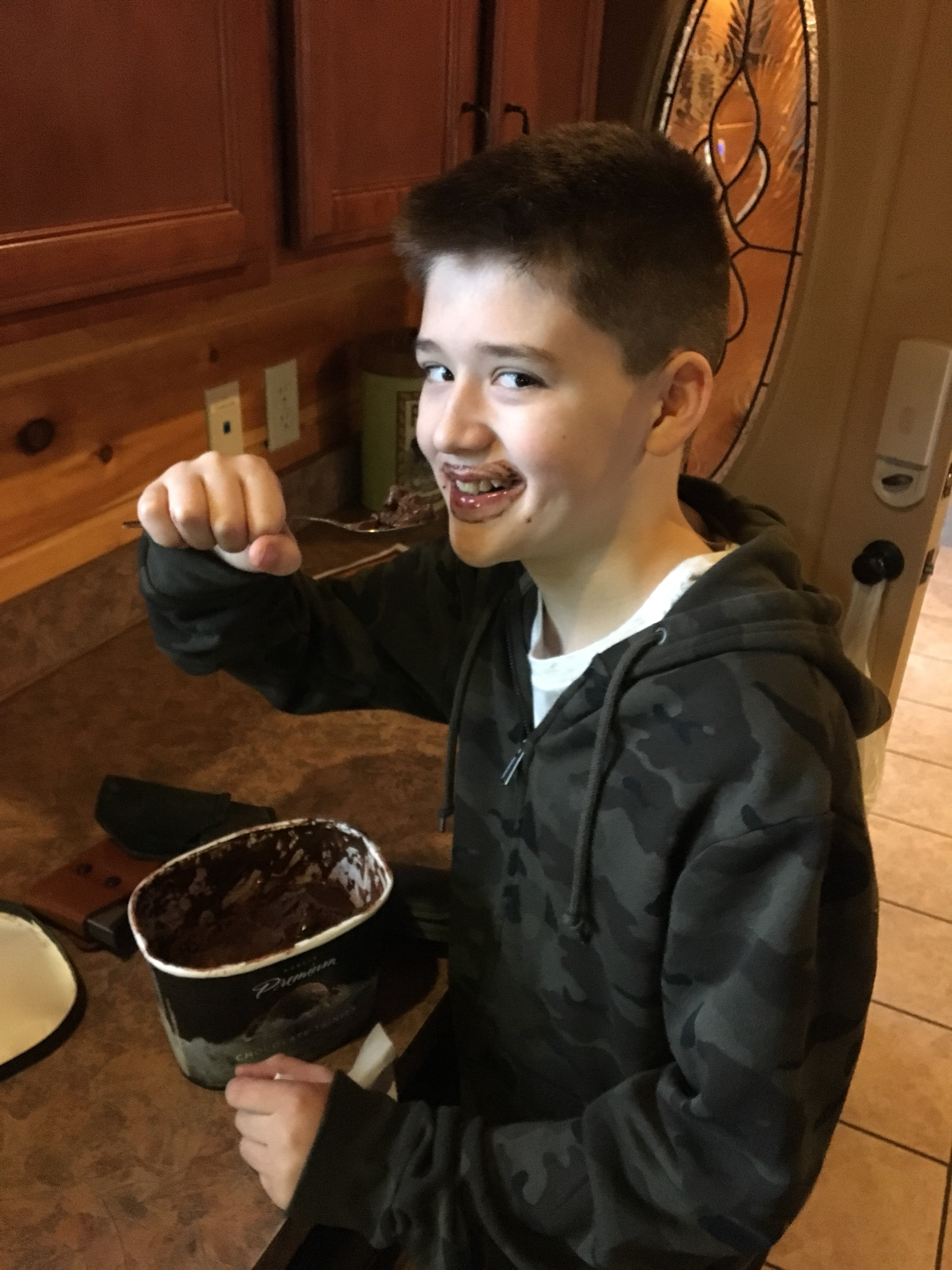 boy eating chocolate ice cream out of gallon with a spoon 