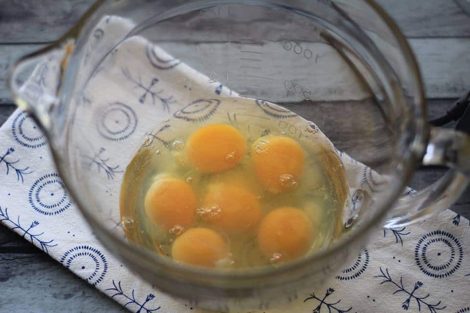 Six cracked eggs in a clear bowl