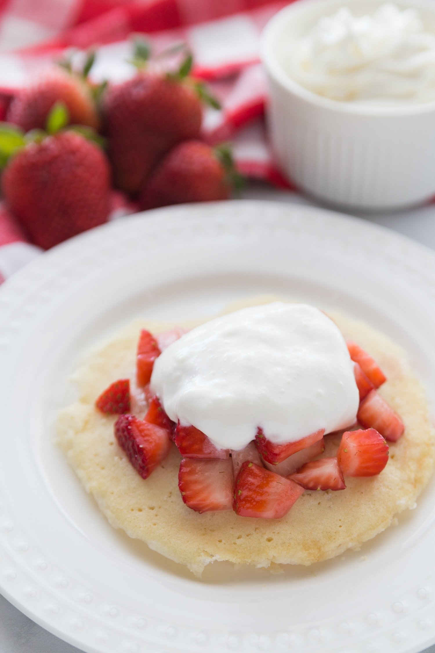 low carb strawberry shortcake on white plate with whole strawberries in background