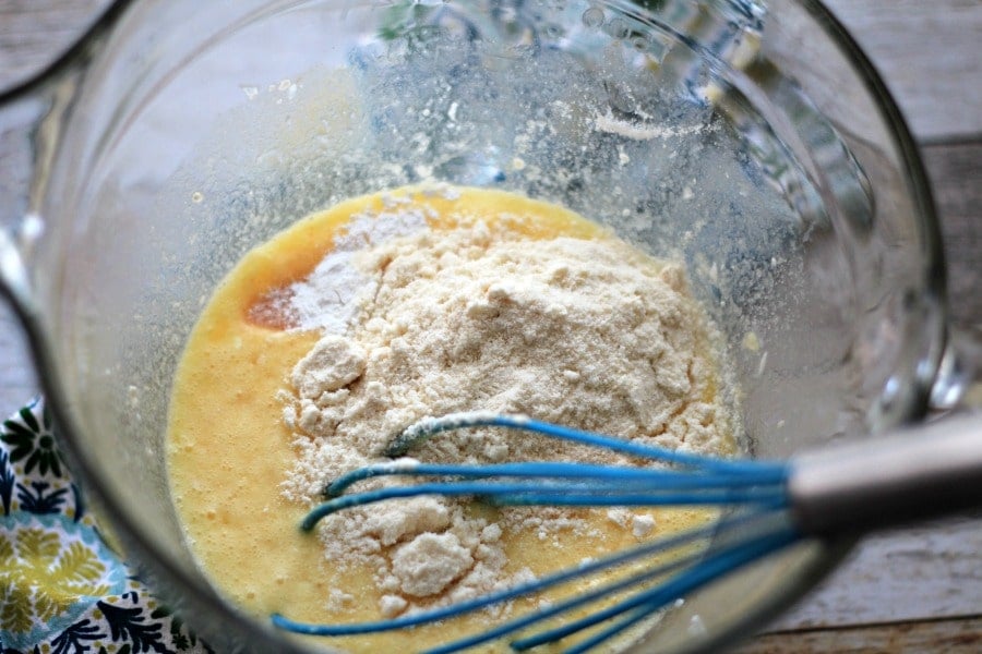 coconut four added to egg and butter mixture in a glass bowl with a whisk. 
