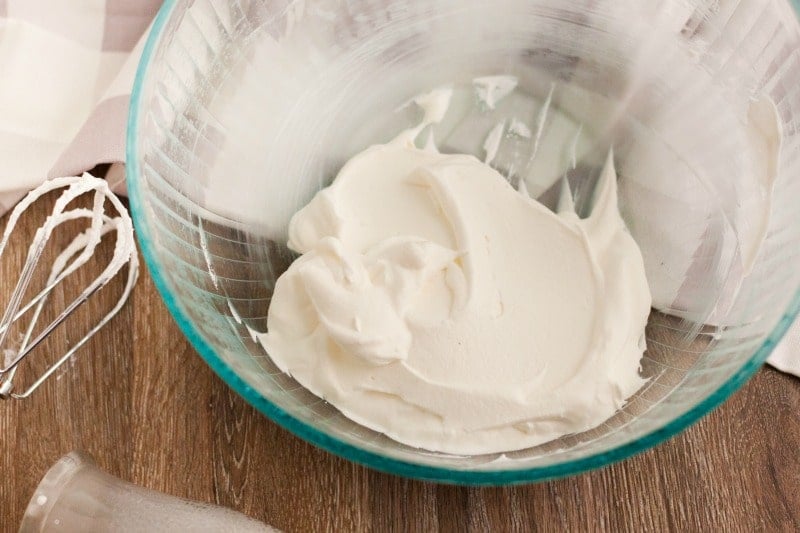 Heavy whipping cream mixed in clear bowl with a whisk 