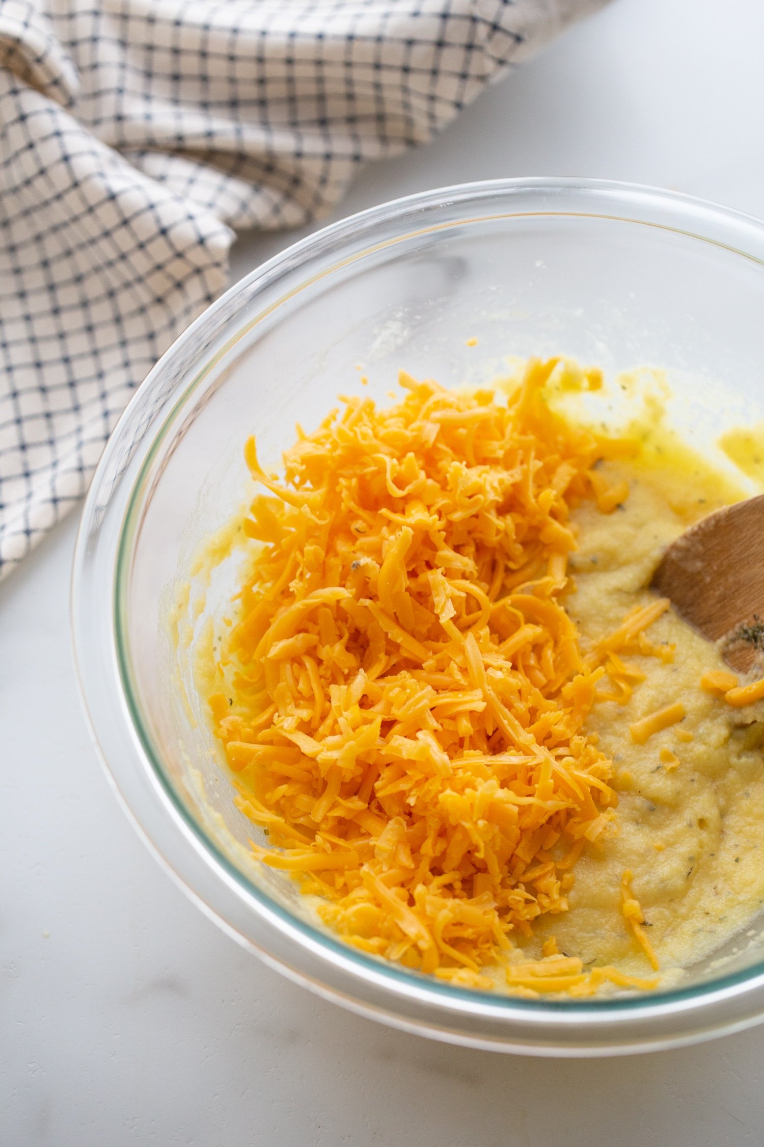 shredded cheddar cheese in a bowl with eggs and cream