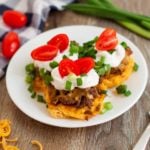 taco cups plated garnished with sour cream and tomatoes