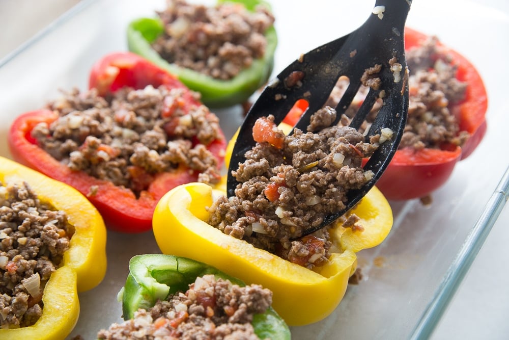 Ground beef mixture being put in bell peppers for low carb stuffed peppers
