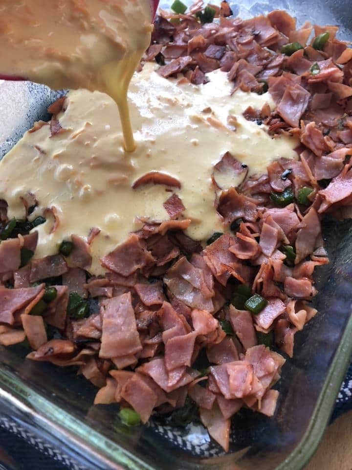 Pouring egg mixture into browned ham and peppers