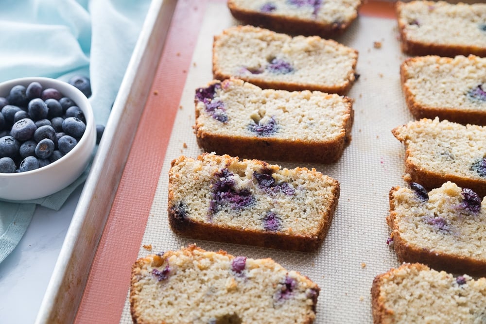 Slices of keto blueberry bread on a baking sheet for toasting