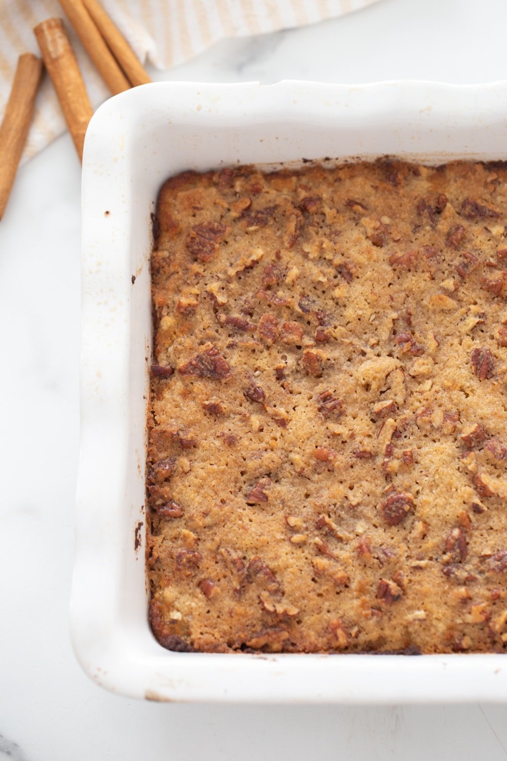baked low carb cake in a white baking dish with pecan topping 