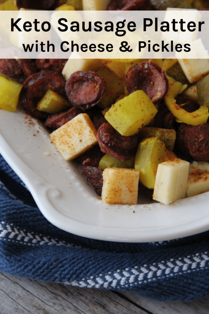 Close-up photo of an appetizer platter of thinly sliced smoked sausages with cubed cheese, dill pickle chunks and sliced banana pepper rings, served as part of a low-carb high-fat keto diet.