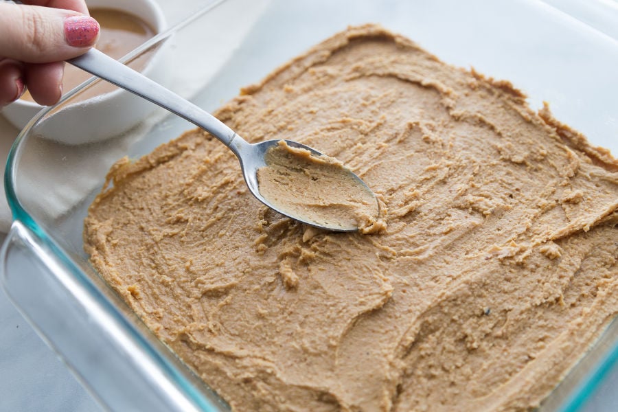 keto no bake peanut butter bars spread in baking dish with a spoon