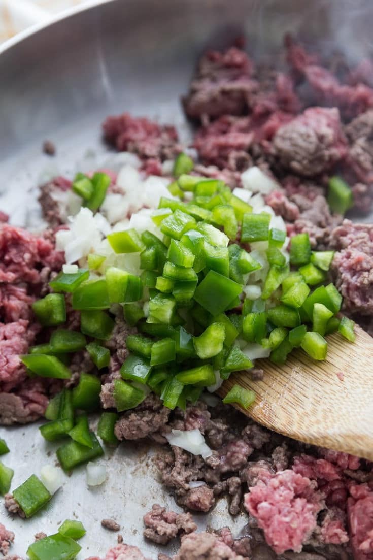 Browning Ground Beef, green peppers, and onions in a skillet 