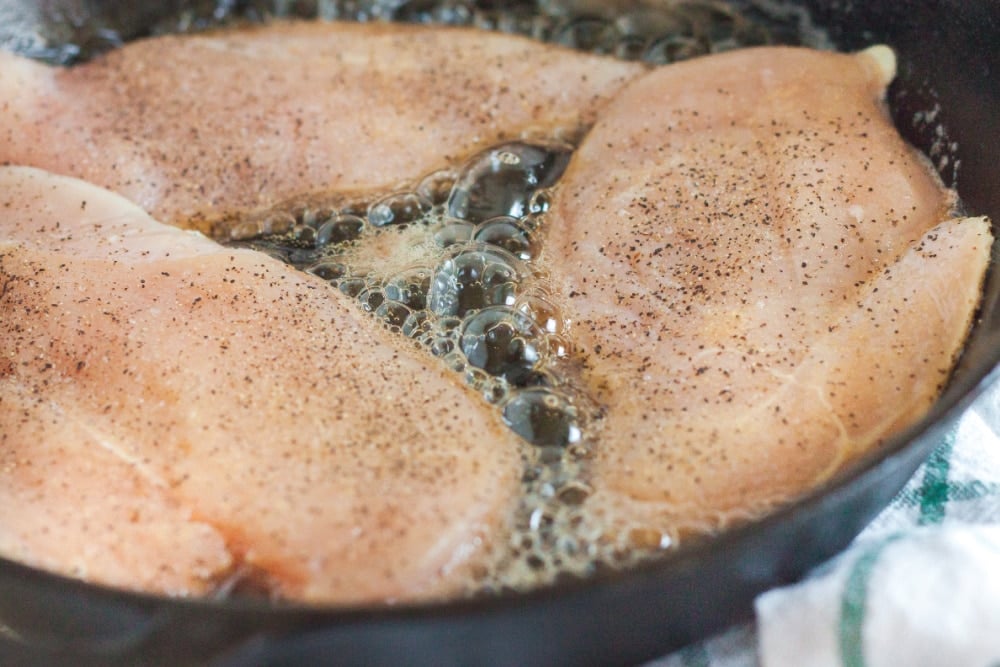 raw thin cut chicken breasts in a cast iron skillet