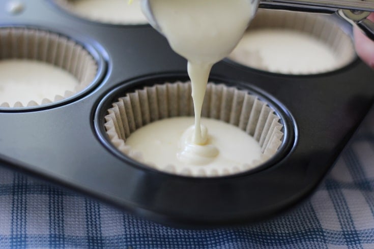 Lemon Blueberry low carb cheesecake batter being poured out into muffin tin.