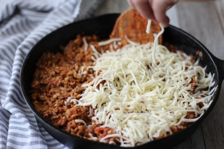 Beef mixture with mozzarella cheese being sprinkled over the top.