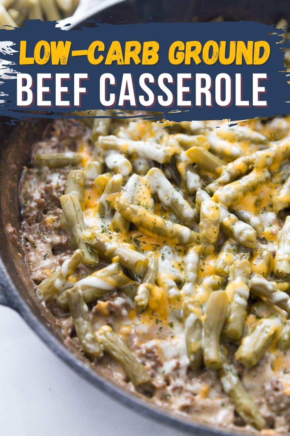 cast iron skillet with a keto and ground beef casserole topped wit green beans and cheese close shot