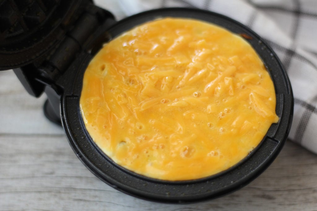 cheese waffle batter poured in dash waffle maker
