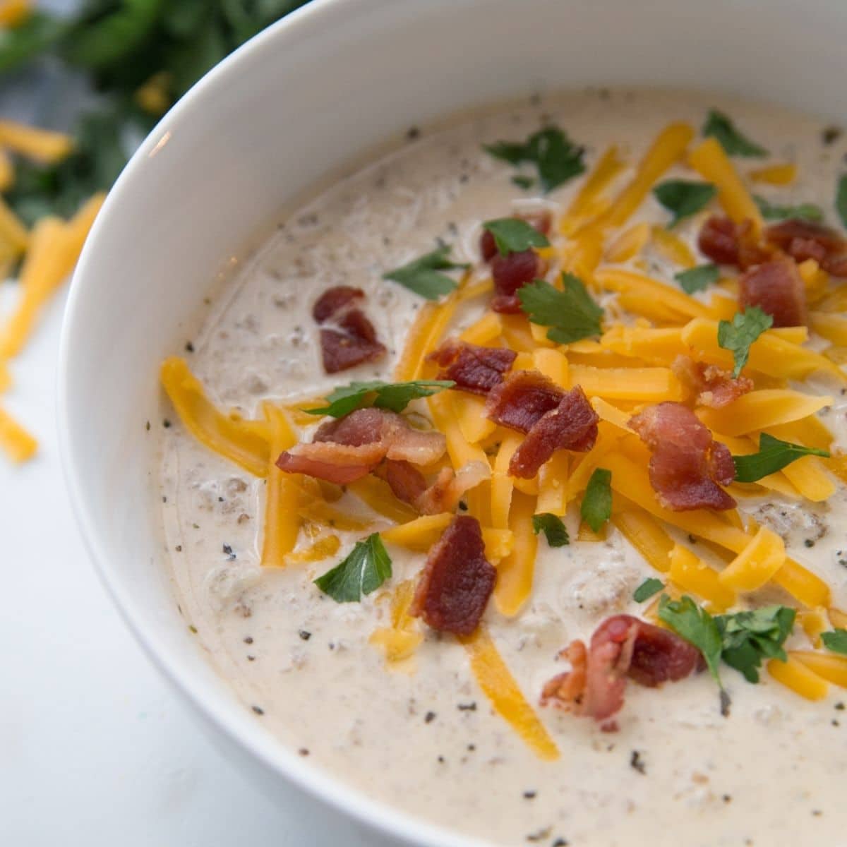 keto cheeseburger soup in a white bowl with cheese and bacon