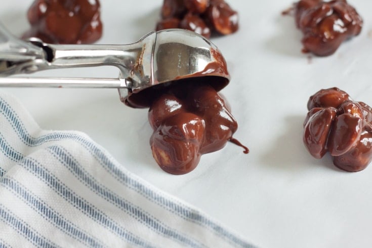 scooping out keto chocolate macadamia nut bites on parchment paper