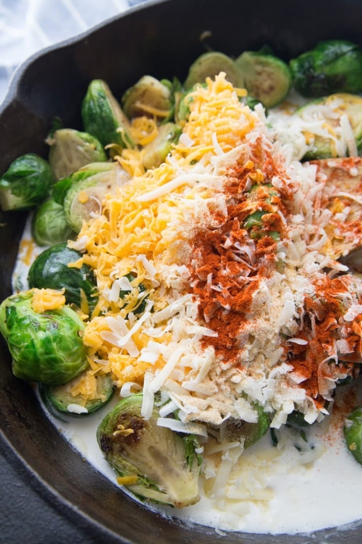 Brussels sprouts with cheeses and spices added to the skillet