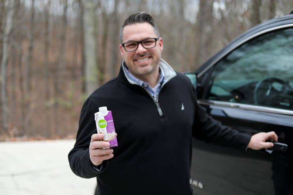 man holding keto shake getting in the car