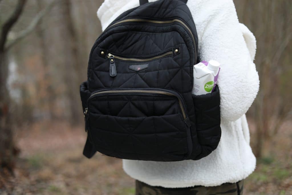 lady from behind with a backpack diaper bag and a ZonePerfect Keto Shake in the pocket on bag