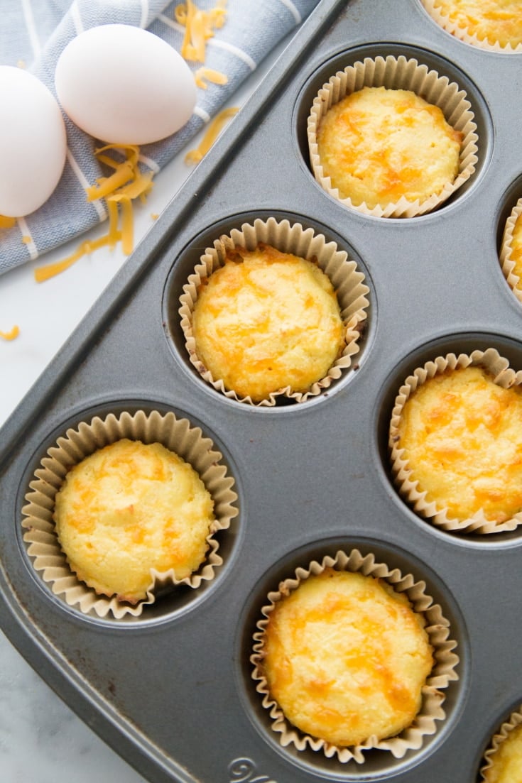 Image of a muffin pan filled with bicuits fresh out of the oven in muffin cups.