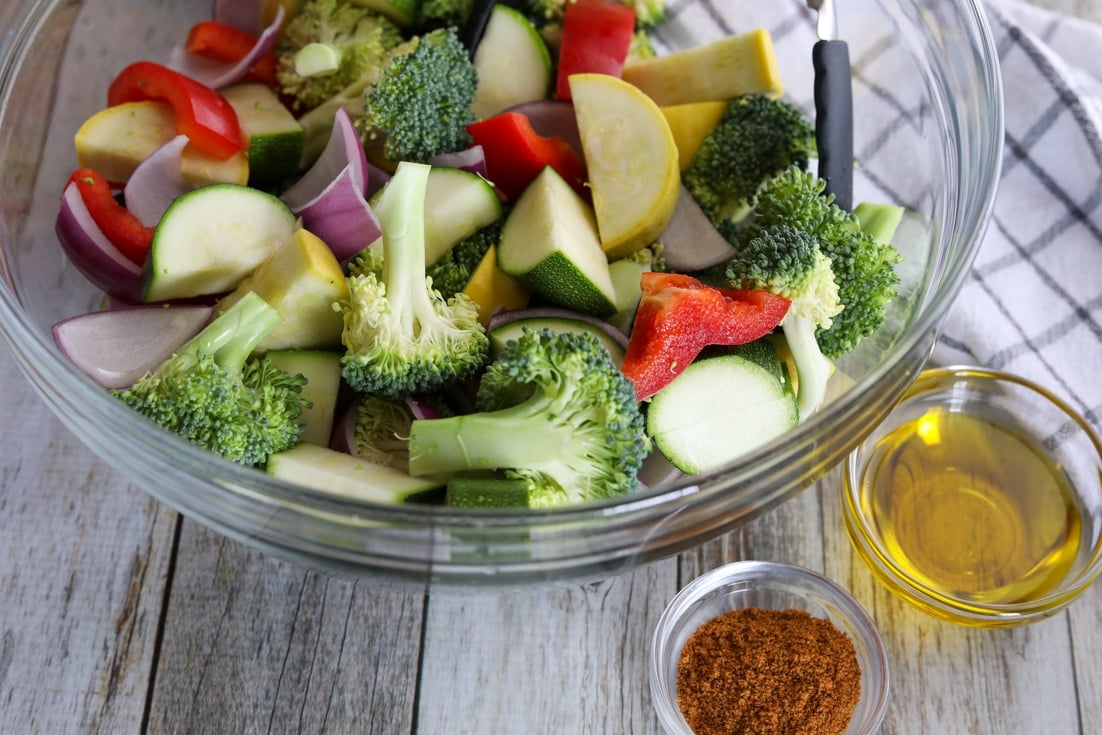 raw cut vegetables in a bowl with oil and seasoning