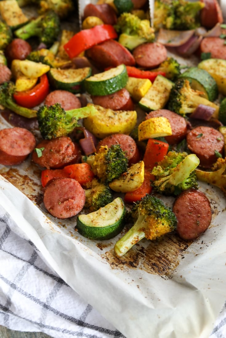 Baked sausage and vegetables seasoned and laid on a sheet pan