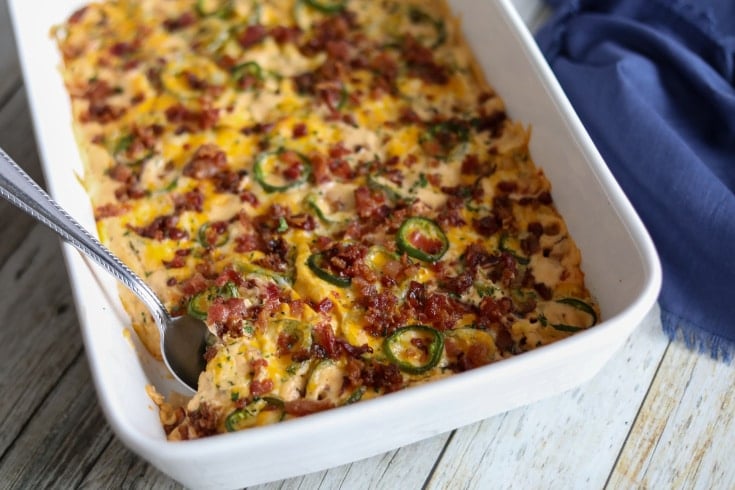 chicken casserole in a white baking dish topped with cheese and jalapenos