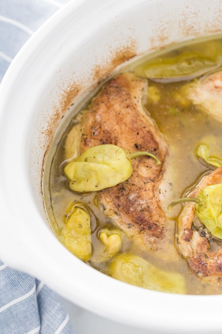 Cooked chicken in a crock pot with juices.