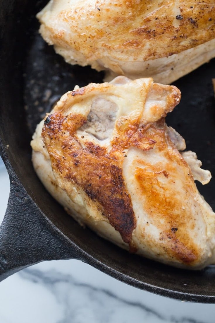 Seared chicken breasts in a cast iron skillet.