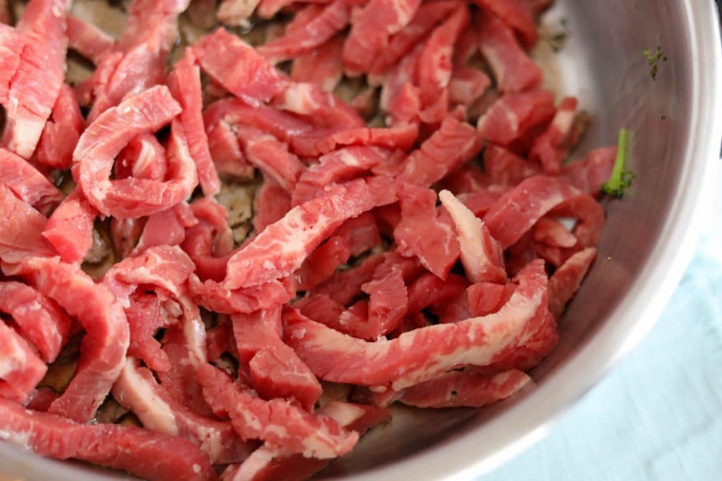 sliced raw flank steak in skillet