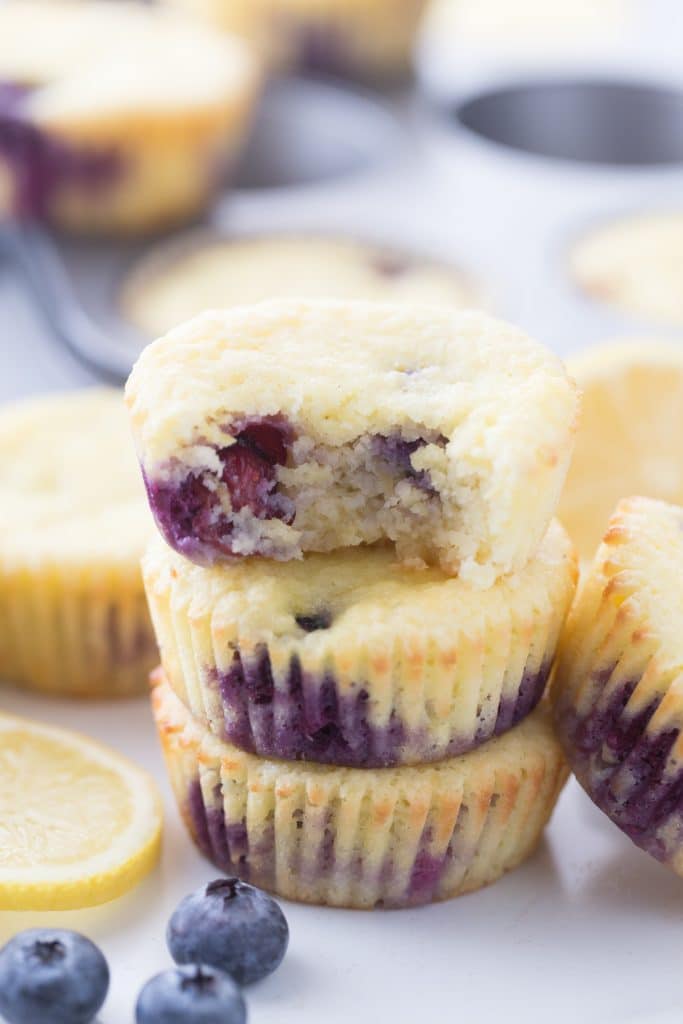 three blueberry lemon muffins stacked with a bite taken out of one