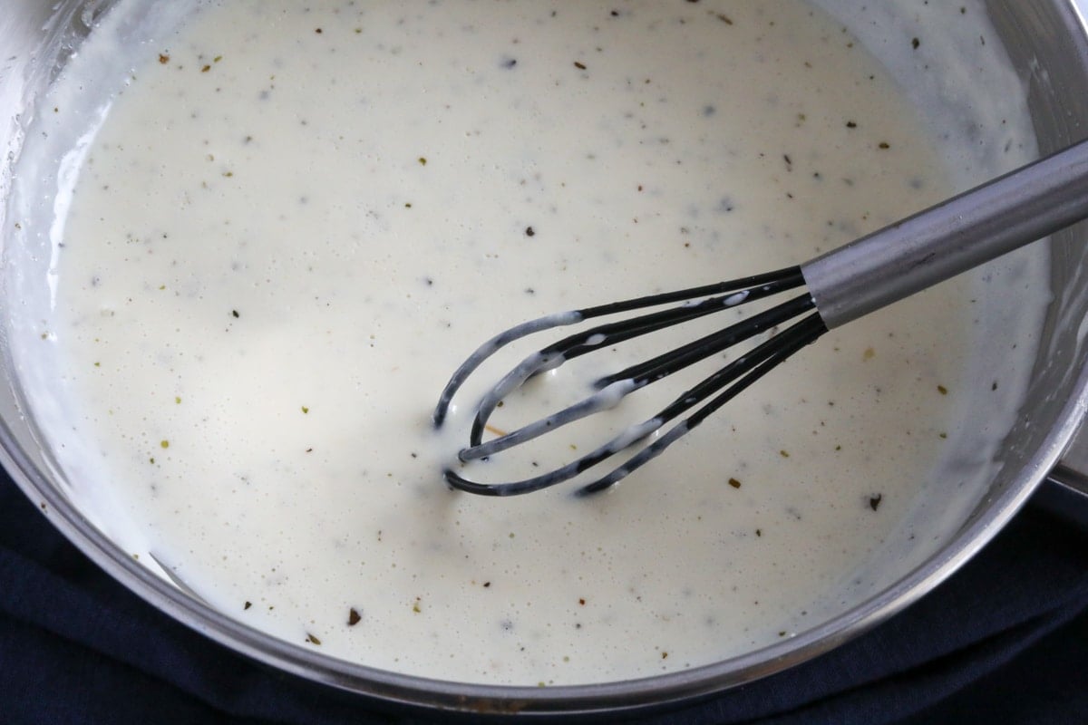 The cream sauce combined in a sauce pan with a whisk.