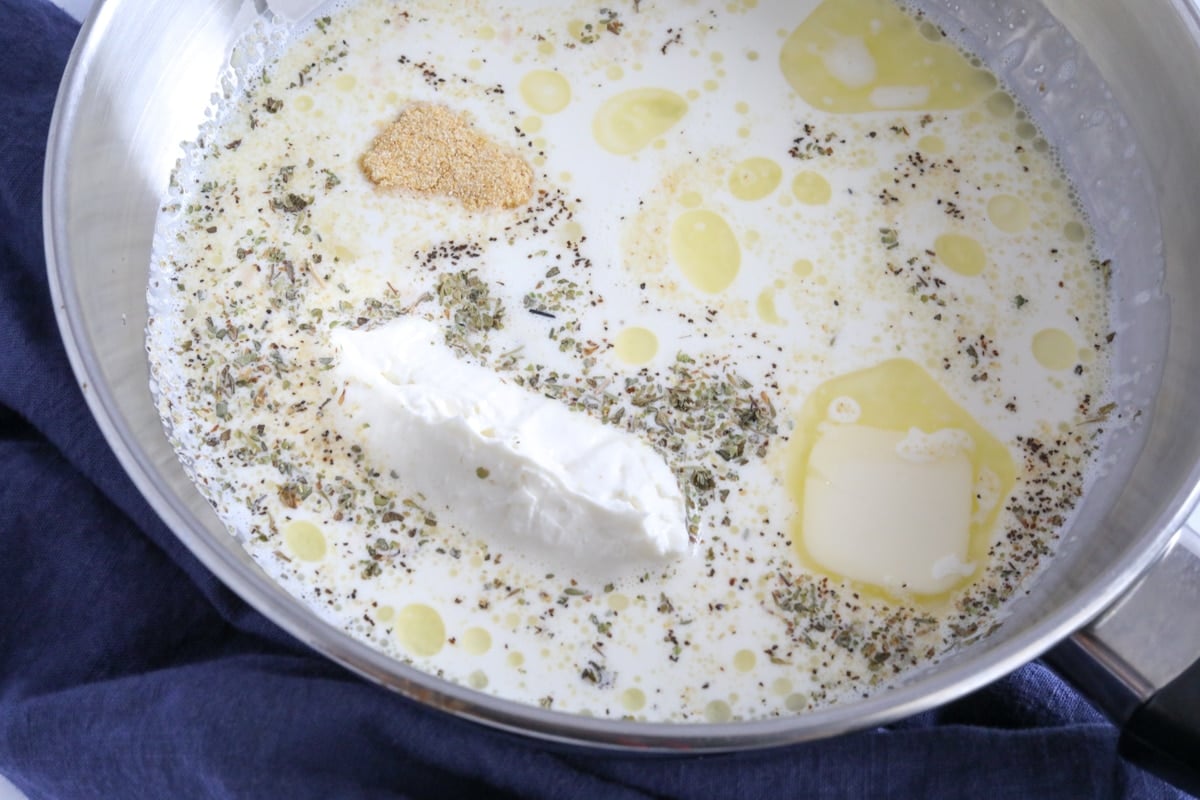 Heavy whipping cream, cream cheese, butter, and other seasonings in a sauce pan.