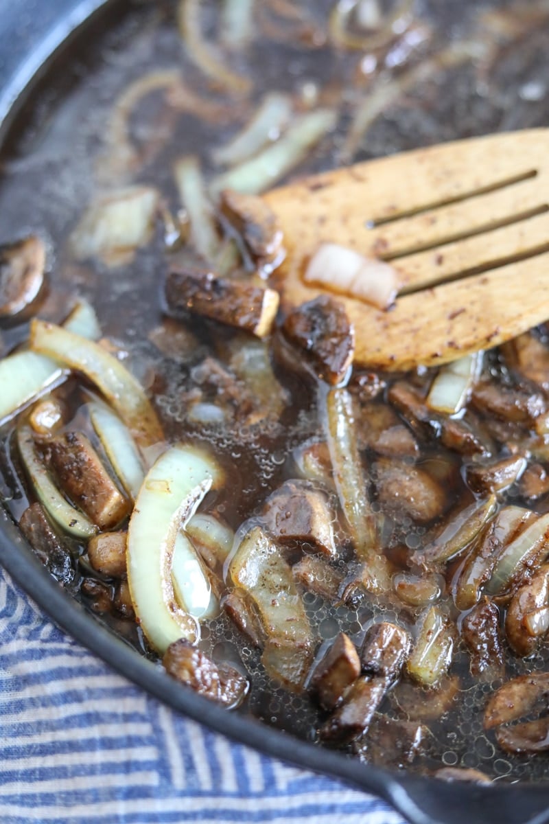 mushrooms, onions and beef broth simmering in a skillet
