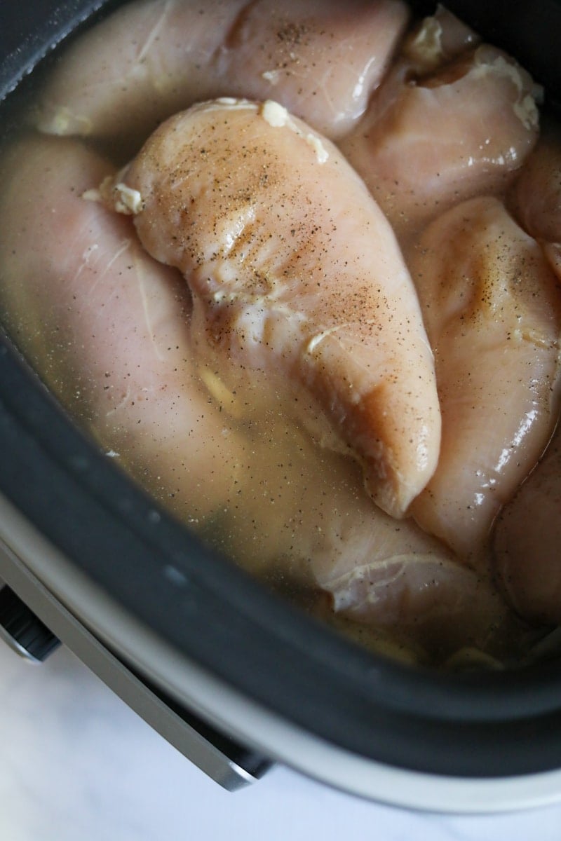 Raw chicken breasts with seasoning in the crock-pot