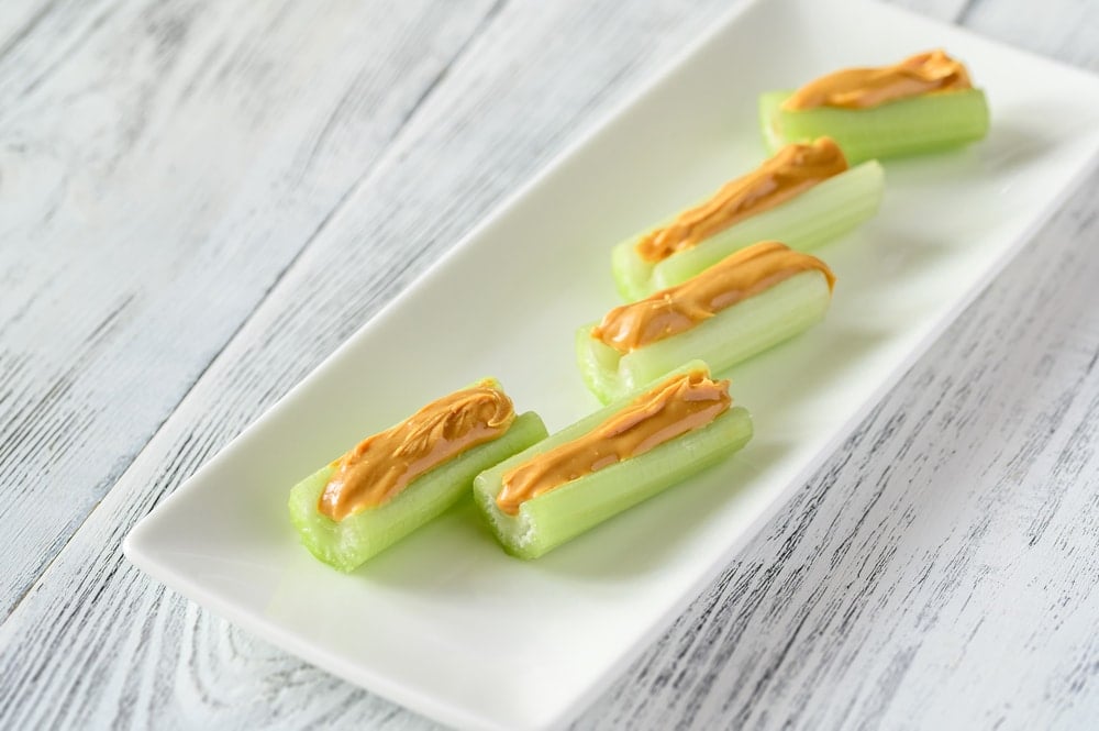sticks of celery with peanut butter inside on a serving plate